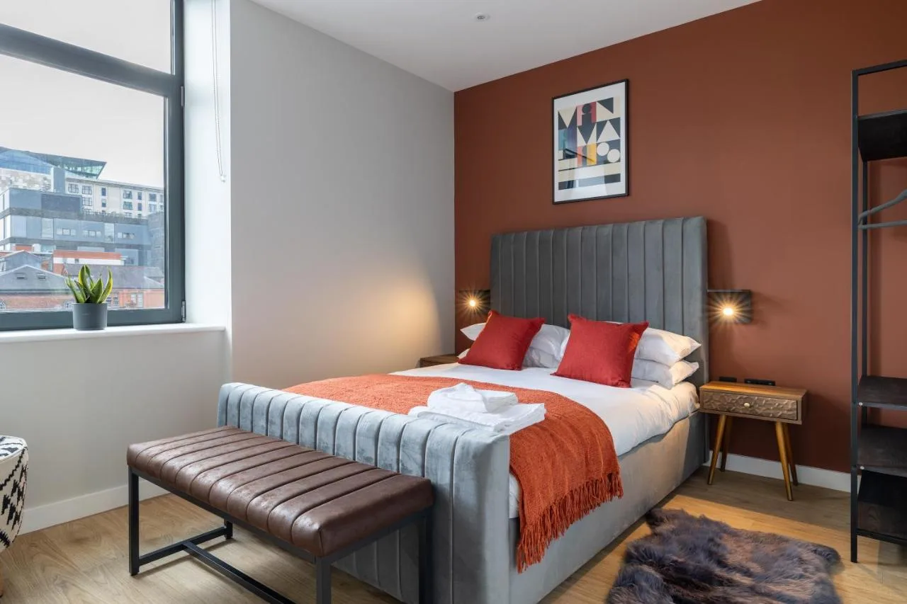 A bedroom with a bed with red pillows and a window at Kula Birmingham - New Street Station