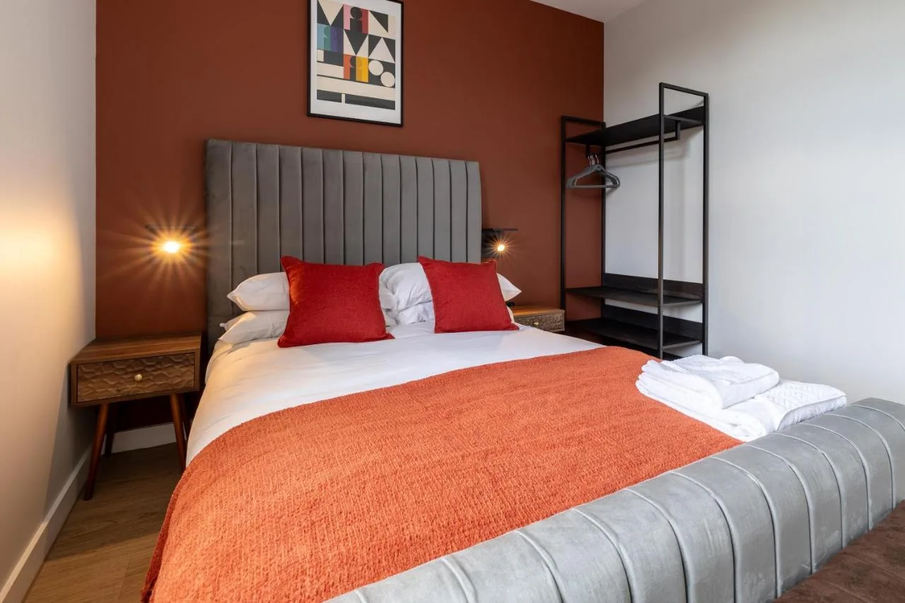 A bedroom with a large bed with red pillows at Kula Birmingham - New Street Station