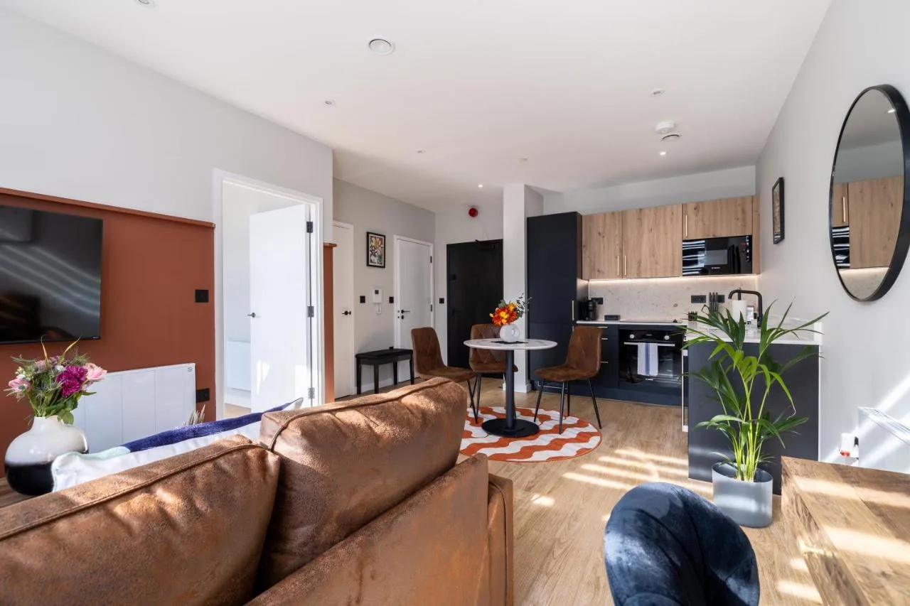 A living room with a couch and a kitchen at Kula Birmingham - New Street Station