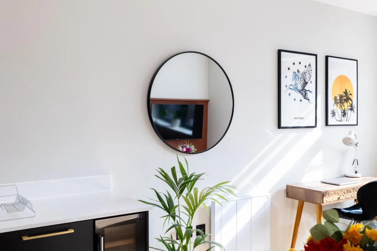 A mirror hanging on a white wall with a desk at Kula Birmingham - New Street Station